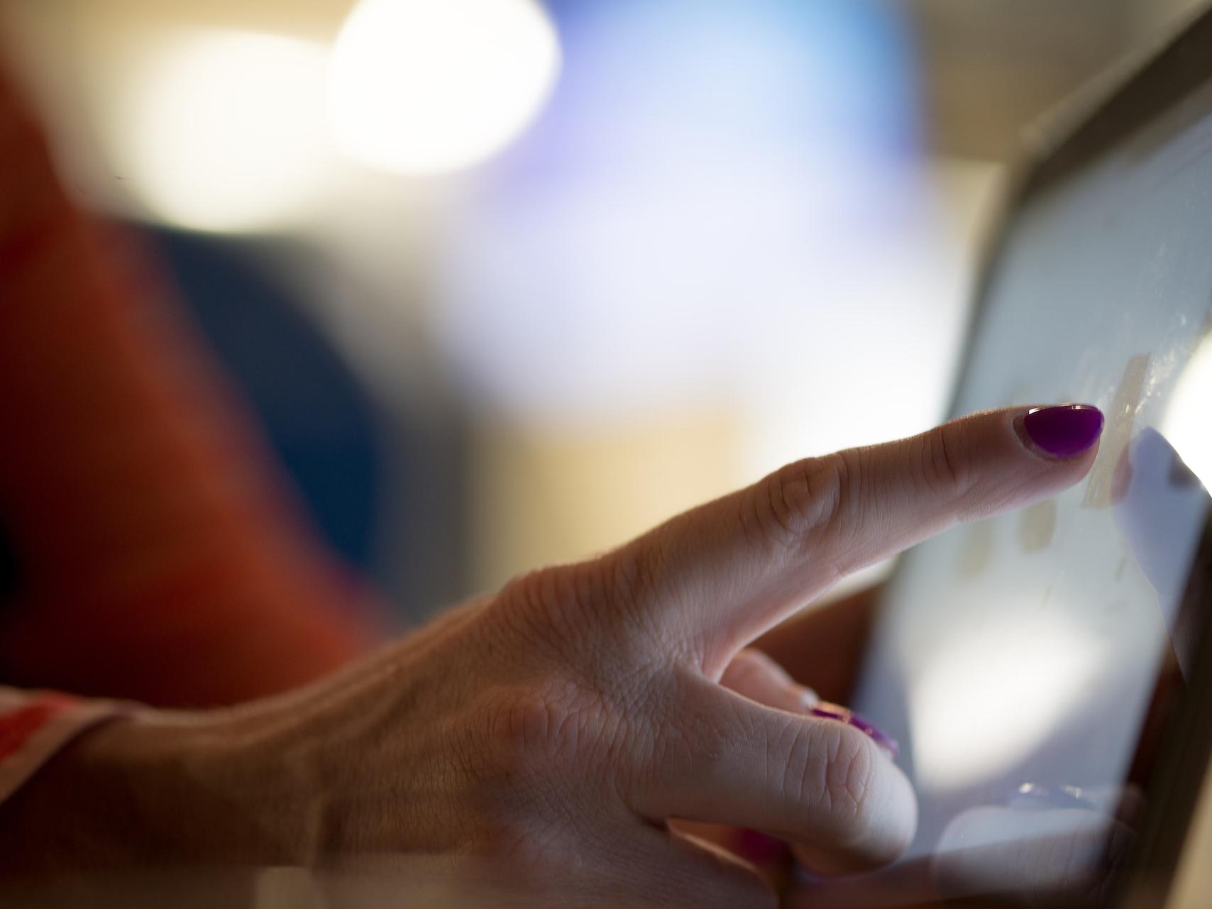 selective focus photography of person pointing at tablet computer